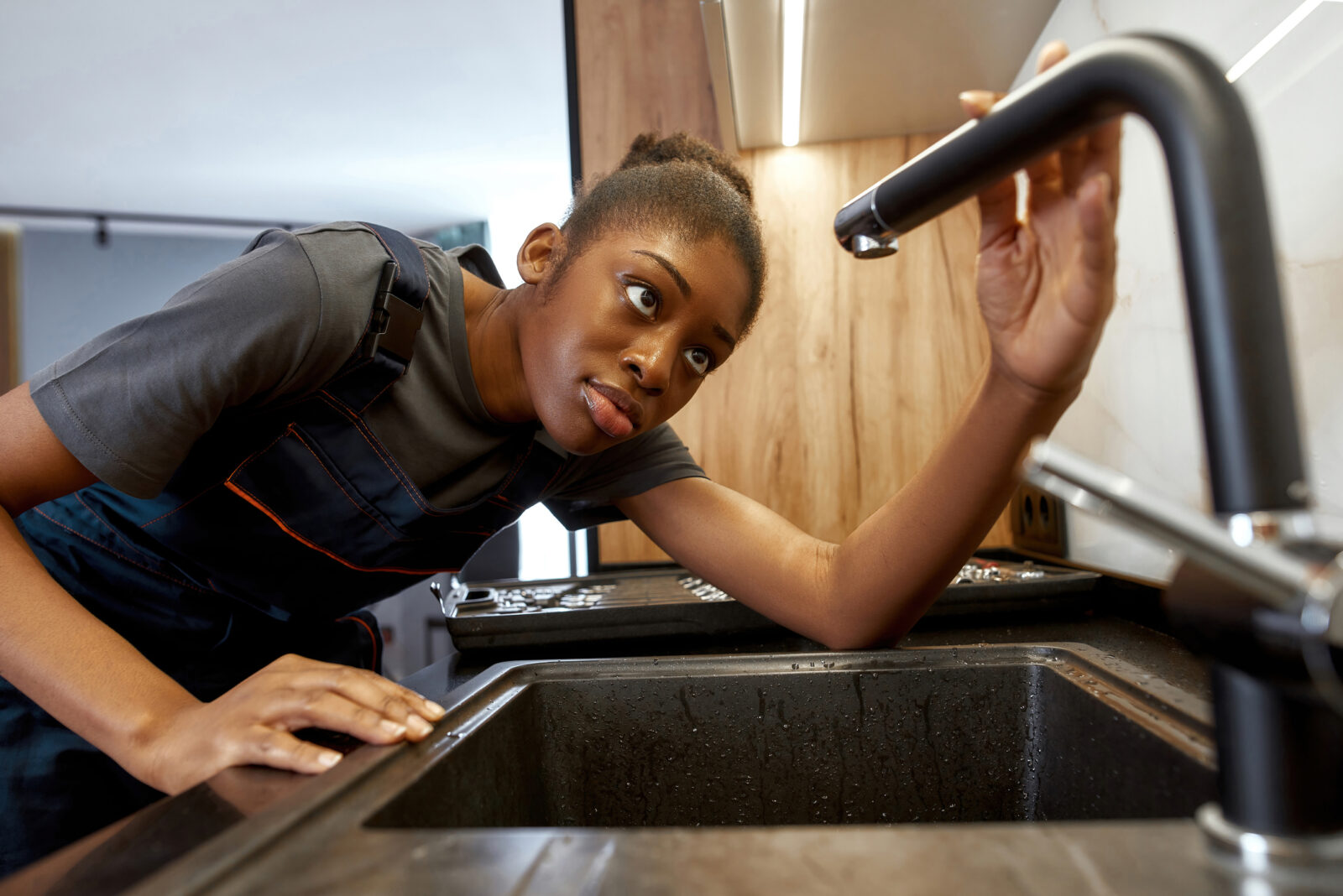 A picture of a woman checking her faucet for leaks, during Fix a Leak Week. LCA