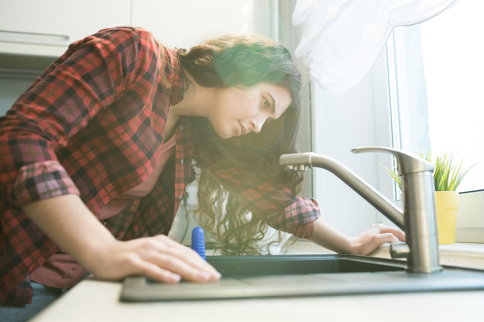 A picture of a woman examining her sink for leaks to illustrate an LCA post on Fix a Leak Week 2023.