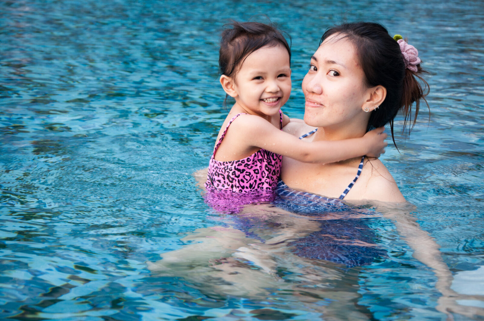 A picture of a young woman having fun and holding a young girl in a swimming pool, to illustrate a post on water safety.