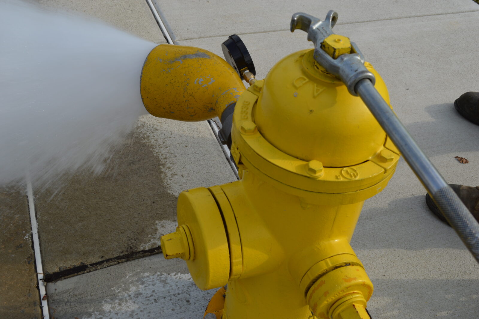 A picture of a hydrant being opened with a hydrant wrench and water streaming out, during a repair. It illustrates an LCA blog post for fire prevention week and month.